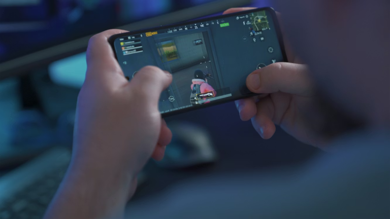 A player holding an Android phone in landscape during a competitive mobile shooter match