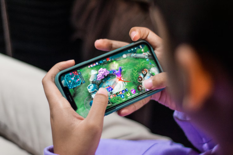 A person playing a mobile game on an Android phone held in both hands during a long evening session