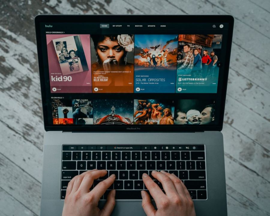 Hulu website opened on Macbook with person hands on keyboard