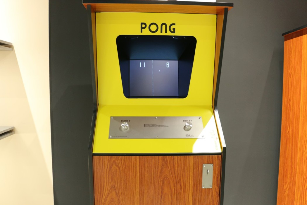 A yellow arcade machine sitting on top of a wooden floor