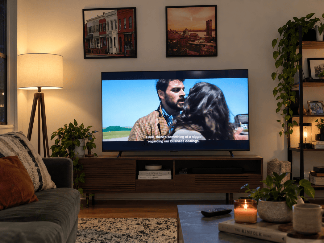Hisense M7SR playing a sunlit movie scene with subtitles in a lamp-lit living room